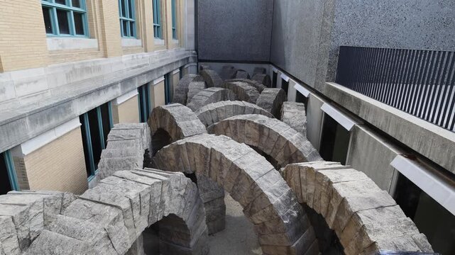 Stone arches sculpture in urban courtyard.