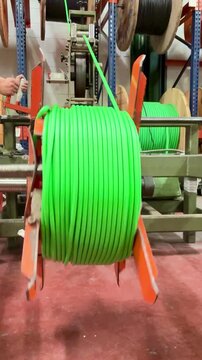 Large wooden reel with green industrial electrical cable prepared for installation and distribution