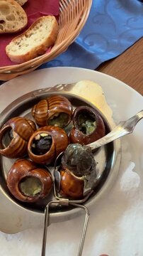 Eating traditional French escargots snails with garlic butter in a restaurant