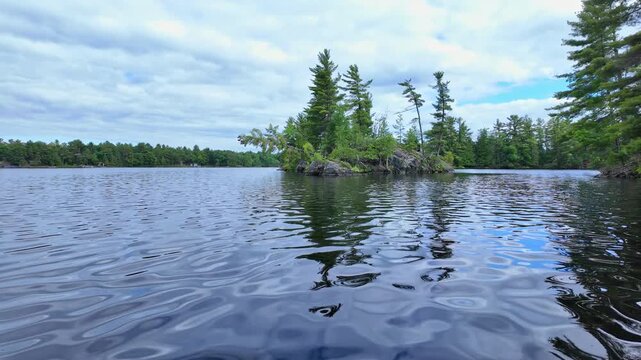 POV view moving boat gliding over rippling blue water. Gentle waves under a cloudy sky as the camera drifts steadily forward. Calm, cinematic lakeside backdrop.