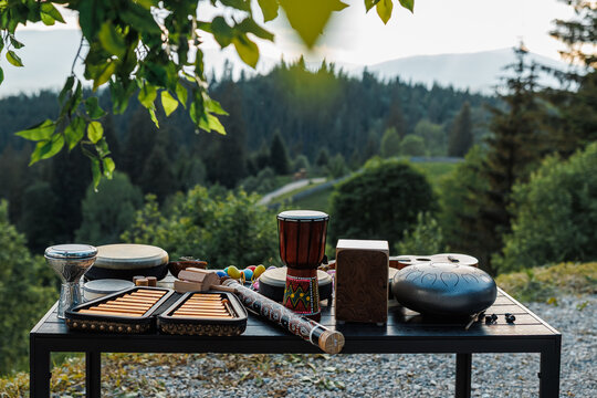 Assortment of ethnic musical instruments on a table with a scenic mountain background.