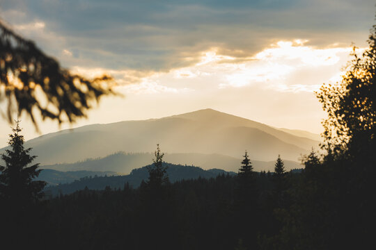 Golden hour over the Carpathian mountains with sunbeams breaking through clouds.