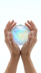 Obraz premium Hands holding iridescent crystal sphere with rainbow light reflections on white background, isolated for design use and spiritual concepts.