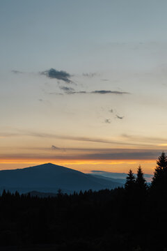 Beautiful evening twilight with bright orange sky above dark mountain ridges.