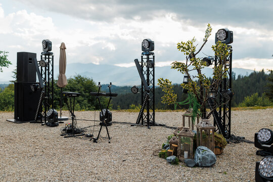 Outdoor concert stage setup with lighting equipment and sound system in the mountains.