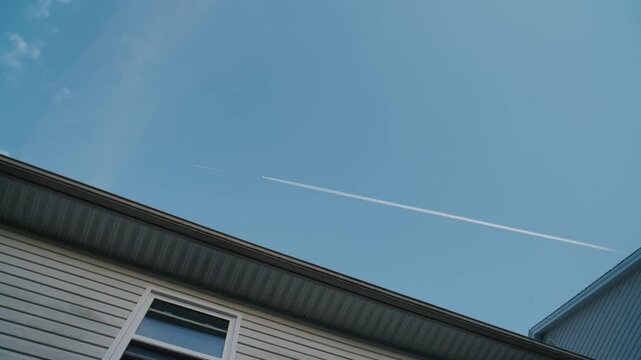 High above the rooftops, soaring paths of planes paint the azure sky