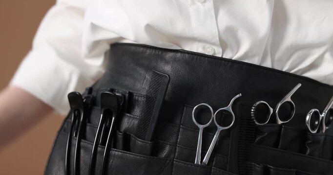 Professional hairdresser with tools belt on brown background, closeup