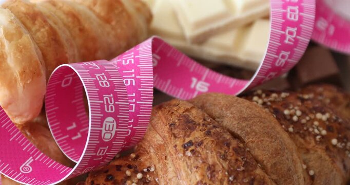 Measuring tape and desserts on table, spinning. Closeup view