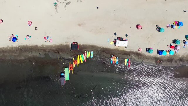 Drone Horizontal Tracking Top Down View over a Packed Sandy Beach with Kayaks and Umbrellas, Chile