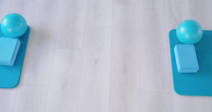Pale wood floor centering as camera shifting mats vertically, foam blocks, balls, showing symmetry