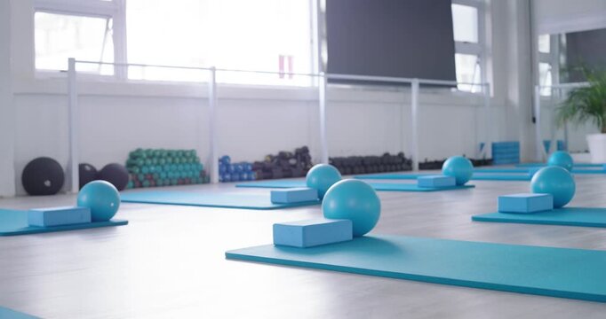 Camera starting low is panning back, revealing blue mat, block and ball set for group class