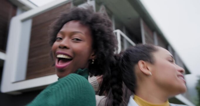 Diverse female friends laughing, turning and rotating by balcony, green top stepping forward posing