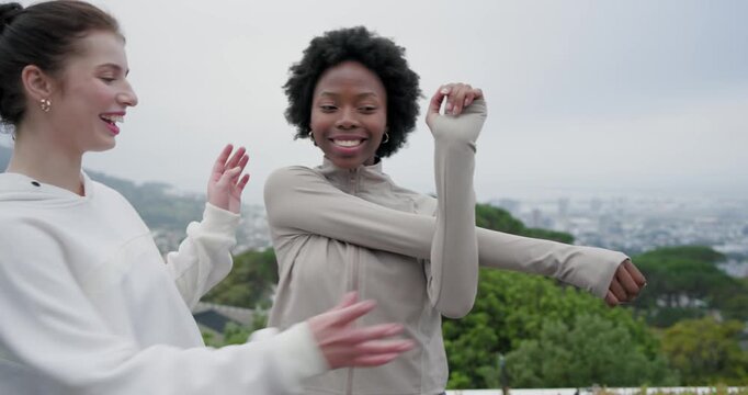 Diverse women walking rooftop deck, one raising arm, hoodie helper guiding and deepening stretch