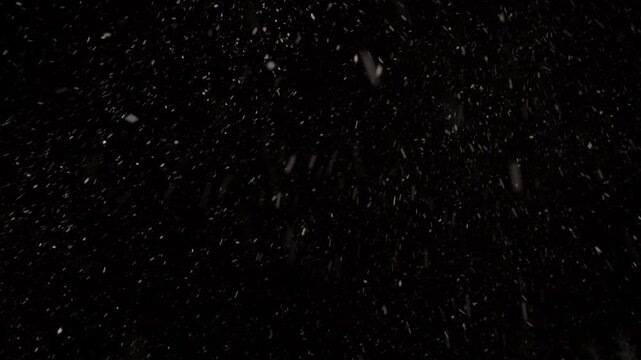 Witness the enchanting dance of snowflakes as they swirl and tumble through the dark night sky, creating a captivating winter wonderland of serenity
