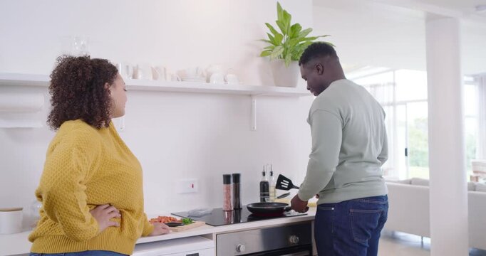 African American couple preparing meal, man stirring frying pan with spatula after chopping veggies