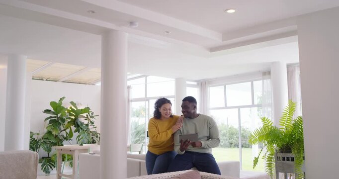 African American couple watching tablet content, man scrolling while woman leaning in living room