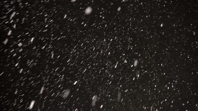 Watch as snowflakes dance in the air, swirling gracefully during a blustery snowstorm against an enchanting black sky filled with winter magic