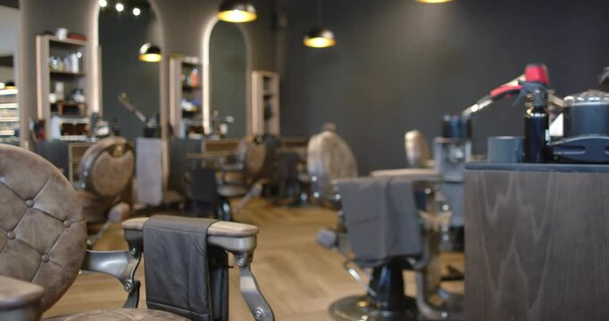Camera is pulling back, revealing tufted barber chair, shelves in empty salon, showing readiness