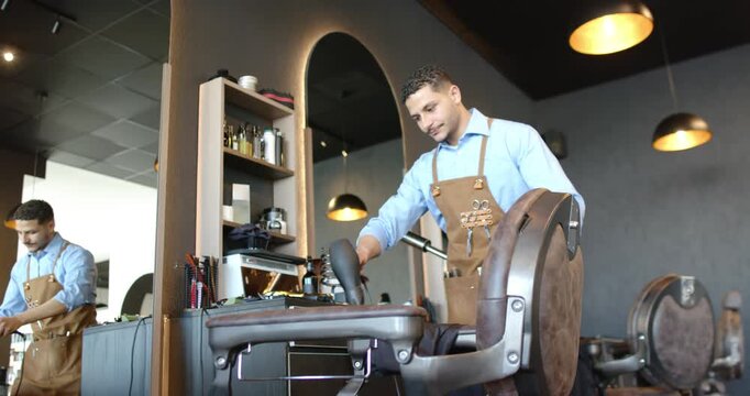 African American barbers wearing aprons adjusting chair headrest testing levers after schedule ping