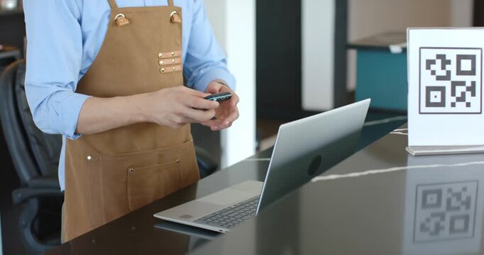 African American man with laptop tapping phone presenting terminal while client tapping card to pay