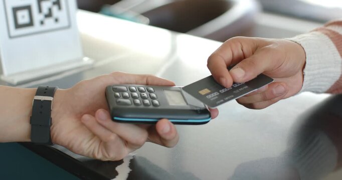 Two men, clerk steadying reader while customer presenting, adjusting chip card at counter paying