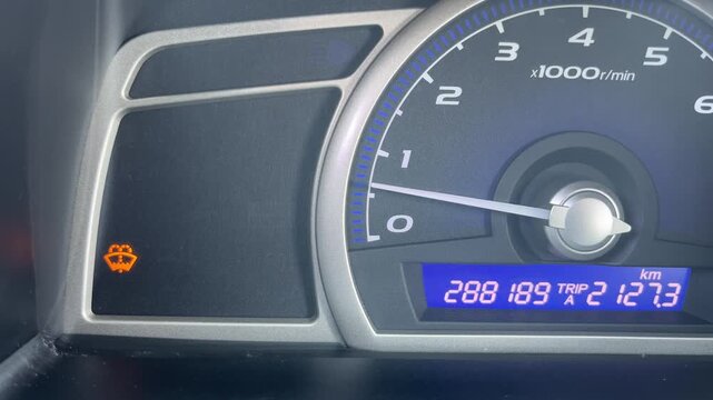 Car dashboard showing windshield washer fluid warning light