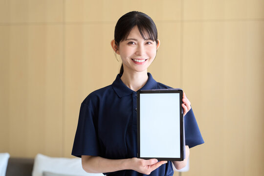 タブレットの画面を見せる清掃業の女性