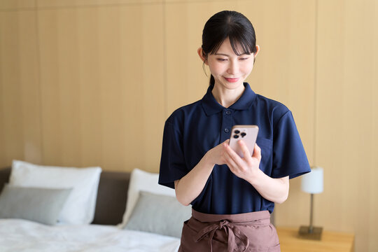 スマホで仕事を管理する清掃業の女性