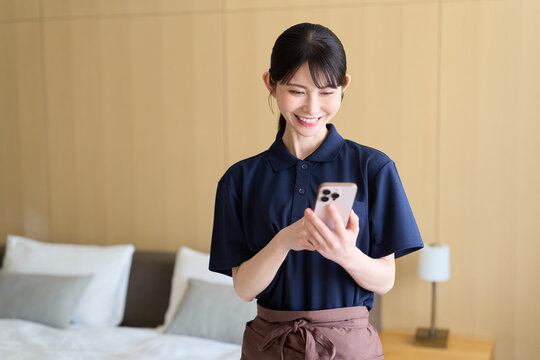 スマホで仕事を管理する清掃業の女性