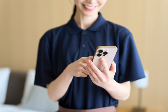 スマホで仕事を管理する清掃業の女性