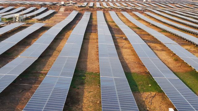 Drone tracking left over rows of photovoltaic solar panels at a utility-scale solar farm, showcasing renewable energy, clean electricity generation, and sustainable infrastructure. 