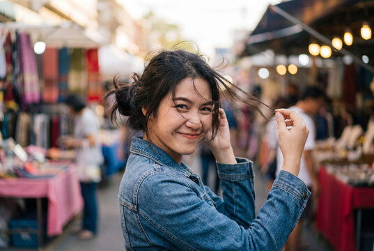 Young woman smiling mischievously holding hair up in pigtails at outdoor street market