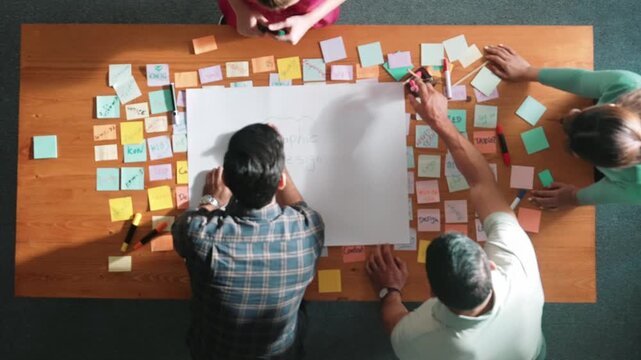Top down view of manager writing and sharing idea by using mind map. Aerial view of smart business team working together and planning by writing in paper and drafting strategy with pencil. Symposium.