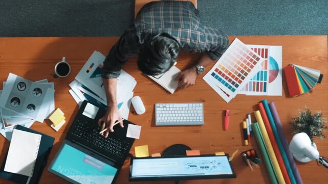 Top view of smart businessman hand choosing color palettes while designing logo graphic. Aerial view of professional interior designer design and select color theme by using color palettes. Symposium.