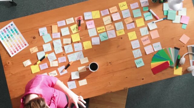 Top view of skilled business woman hold tablet with logo design at meeting. Marketing team working on tablet and walking around table and looking at sticky notes from brainstorming idea. Symposium.
