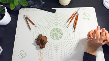 Obraz premium Hands sculpting with brown self-hardening clay close up