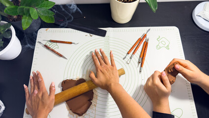 Rolling out brown modeling clay with a wooden rolling pin © Дарʼя Сидорова