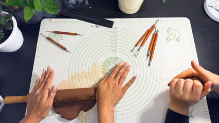 Rolling out brown modeling clay with a wooden rolling pin © Дарʼя Сидорова