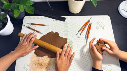 Rolling out brown modeling clay with a wooden rolling pin © Дарʼя Сидорова