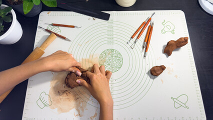 Rolling out brown modeling clay with a wooden rolling pin © Дарʼя Сидорова