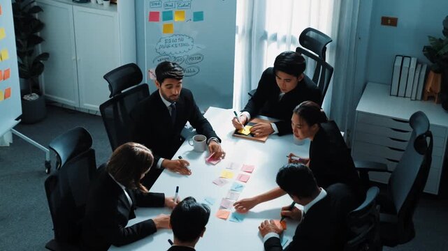 Top view of smart business team brainstorm idea by writing in sticky notes at meeting. Group of professional analysts planning marketing strategy and brainstorming in conference. Teamwork. Directorate