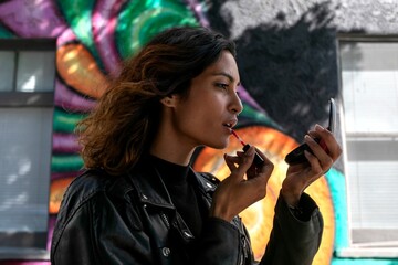 Woman applying lipstick outdoors mural © Rawpixel.com
