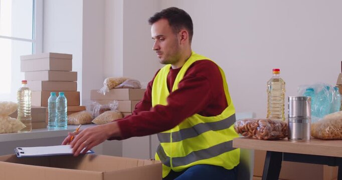 Volunteer busy inspecting food bank distribution service in charitable foundation to make donation, charity, separating donation, stocks control, fixing need provisions, meal warehouse maintenance