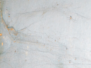 Abstract background of a weathered and distressed wall with peeling paint and plaster in faded light blue and beige tones, showcasing aged texture and grunge details. © Haerudin