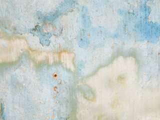 Abstract background of a weathered and distressed wall with peeling paint and plaster in faded light blue and beige tones, showcasing aged texture and grunge details. © Haerudin