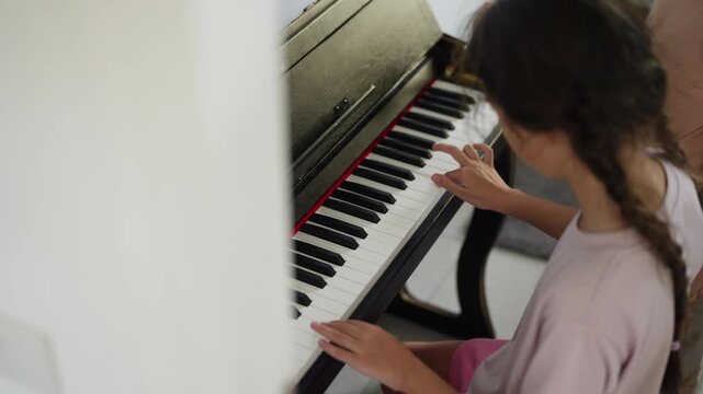 Young girl practicing piano in classroom developing music skills creativity concentration confidence through school music education performing arts training and childhood learning