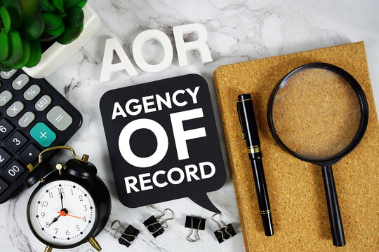 AOR Agency of Record acronym with calculator, alarm clock and magnifying glass, Business concept background