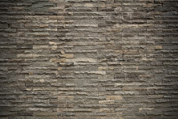 Stone brick wall texture with dark gray rectangular blocks forming a rough architectural surface for interior or exterior design backgrounds. © Okta