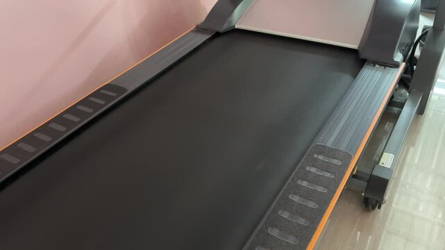 Modern treadmill with sleek dark design Metal rails frame the running belt Flat surface ready for user activity Clean, unused condition shown clearly Ideal for fitness or home workout scenes No people