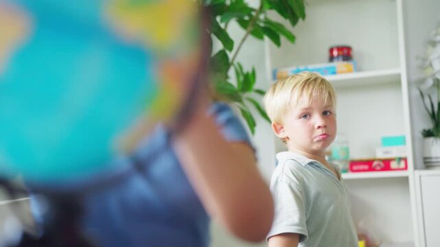 Young preschool boy learning geography using world globe in classroom exploring continents countries and global education during elementary school lesson